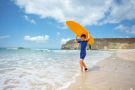 Boy in wetsuit pose with surfboard on seaの写真素材