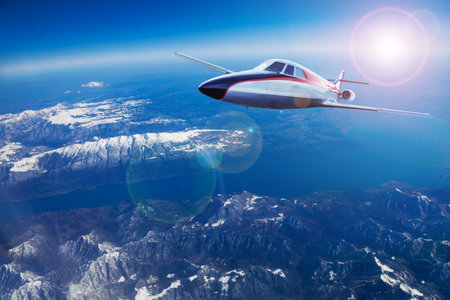Business jet airplane fly over Alps high mountainsの写真素材