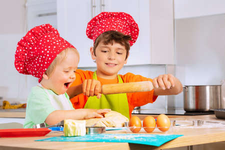 Two children cook, bake cookies wearing chef hatの写真素材