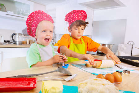 Cute toddler with brother make cookies at kitchenの写真素材