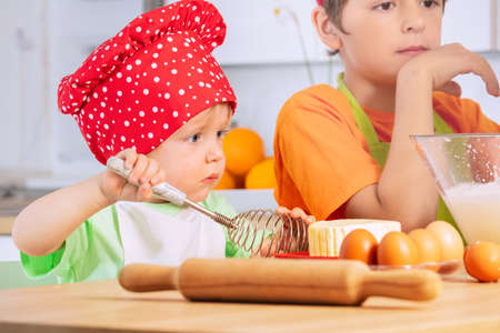 Little boy with whisk cook dough, cookies at homeの写真素材