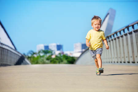 Cute blond toddler boy run on a path walk in parkの写真素材