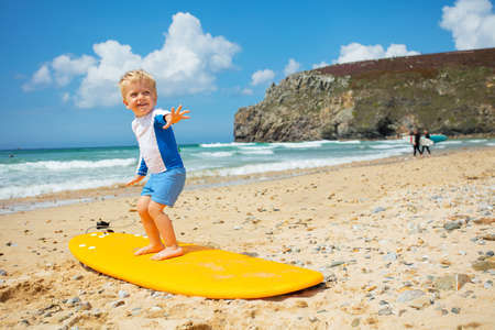 Cute blond toddler boy practice surfboard posingの写真素材
