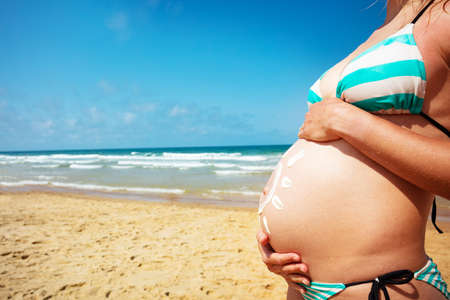 Pregnant belly in bikini next to the seaの写真素材