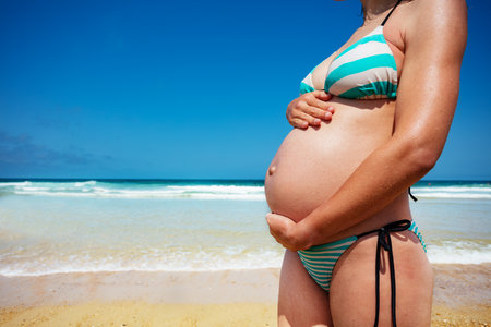 Close-up of pregnant womans belly over the seaの写真素材