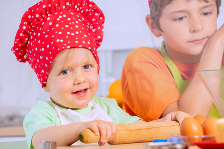 Small toddler boy roll dough plunger in chef hatの写真素材