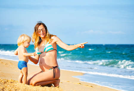 boy with pregnant woman mother point finger at seaの写真素材