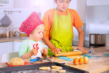Two boys roll dough and cut shapes on the kitchenの写真素材