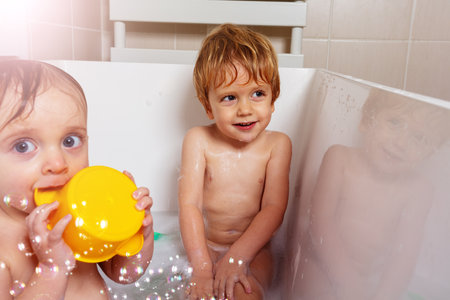 Two happy babies boy and girl sit, play in bathの写真素材