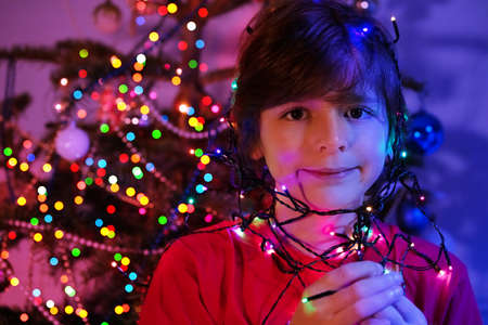 Boy face illuminated by Christmas garland lightsの写真素材