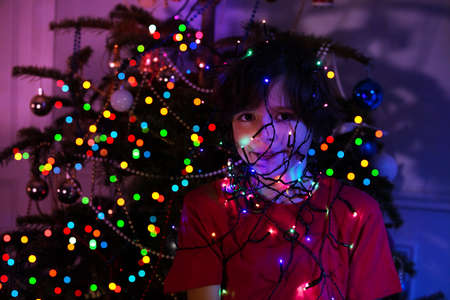 Smiling boy illuminated by Christmas garland lightの写真素材