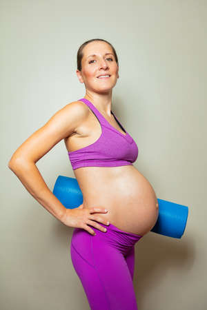 Pregnant woman with big tummy pose hold yoga mateの写真素材