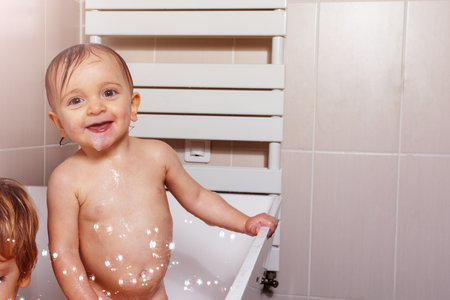 Baby girl happy play in the bath with soap bubblesの写真素材