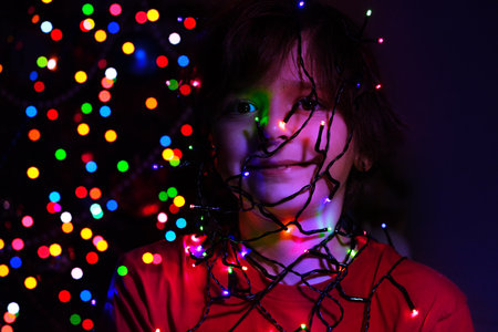 Portrait of a boy with illuminated garland on faceの写真素材
