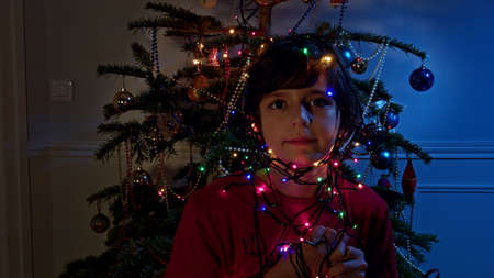 Boy near New Year tree hold color lights garlandの写真素材