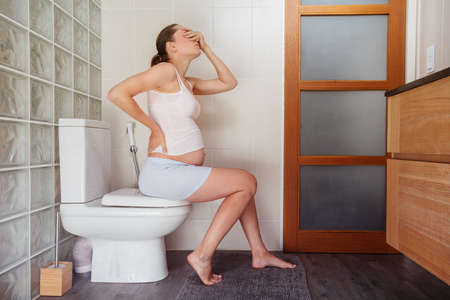Facepalm expression pregnant woman with back problemsの写真素材