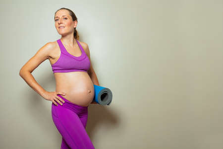 Pregnant woman with big tummy hold fitness mateの写真素材