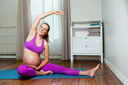 Pregnant woman do stretching exercise at homeの写真素材