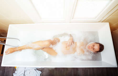 Pregnant woman bath with foam touch belly top viewの写真素材