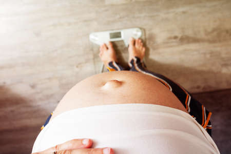 Top view of pregnant womans big belly on scalesの写真素材