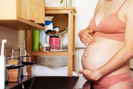 Pregnant woman apply lotion on the belly, close-upの写真素材