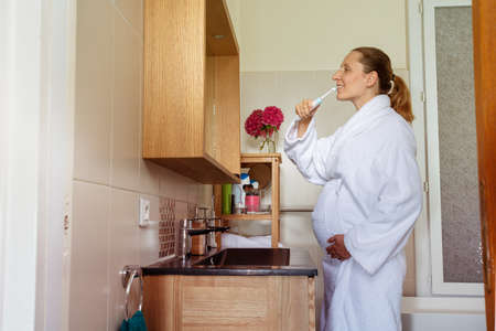 Pregnant woman touch big belly in robe bush teethの写真素材