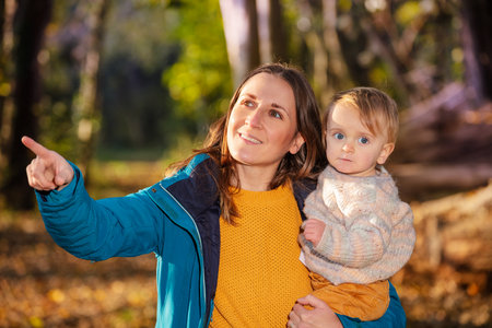 Happy woman holding small kid pointing with fingerの写真素材