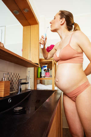 Pregnant smiling woman brush teeth with toothbrushの写真素材