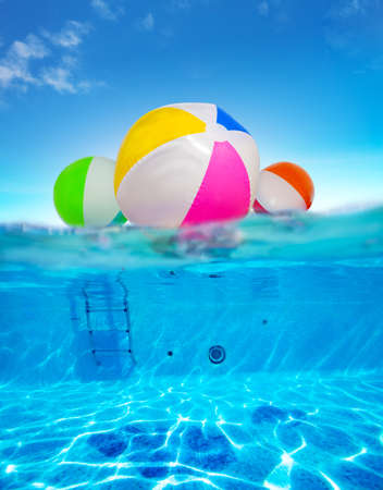 Inflatable balls float in water, split underwater pool imageの写真素材