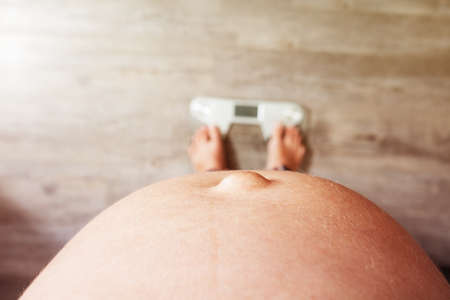 Close-up view from top of pregnant belly on scalesの写真素材