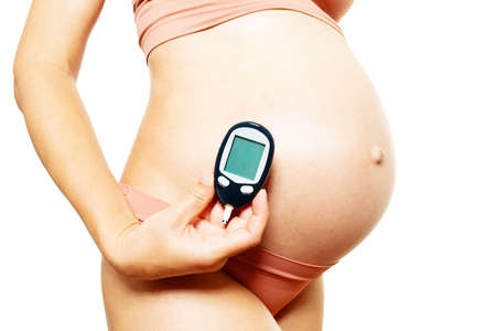 Pregnant woman blood sugar tester near big bellyの写真素材