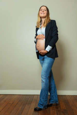 Pregnant woman in suit showing big belly, business conceptの写真素材