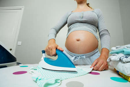 Iron close-up of a pregnant woman ironing newborn baby clothesの写真素材