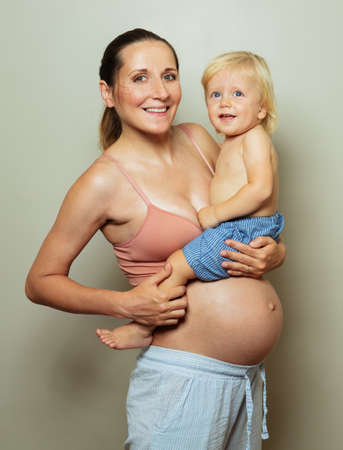 Pregnant mother together with little blond toddler in handsの写真素材
