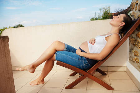 Pregnant woman rest in the long-chair profile viewの写真素材