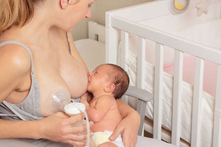 Mother use breast pump and breastfeed baby in nurseryの写真素材
