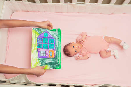 Little baby girl in pink and brother show his drawingの写真素材