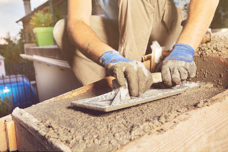 Close-up of a man with trowel make concrete staircase at homeの写真素材