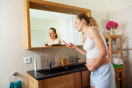 Pregnant woman in pain touch belly calling doctorの写真素材