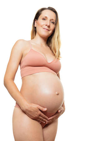 Pregnant woman hold belly in casual underwear over the whiteの写真素材