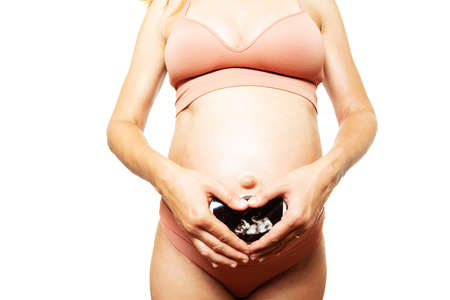 Pregnant womans belly hold hands in heart shapeの写真素材