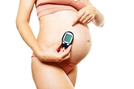 Pregnant woman hold blood sugar tester in handsの写真素材