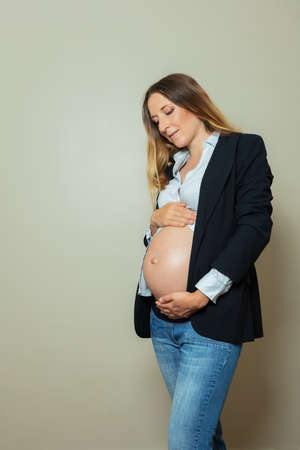 Calm pregnant woman wearing suit showing big bellyの写真素材
