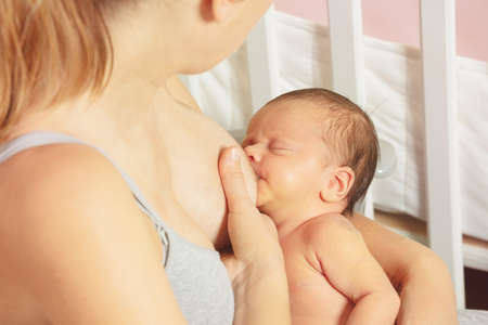 Close-up of a woman breastfeed newborn infant baby sittingの写真素材