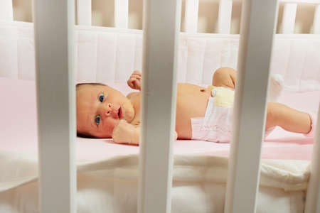 Portrait of an infant laying in the baby crib at homeの写真素材