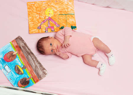 Little newborn baby girl lay in the pink crib with drawingsの写真素材