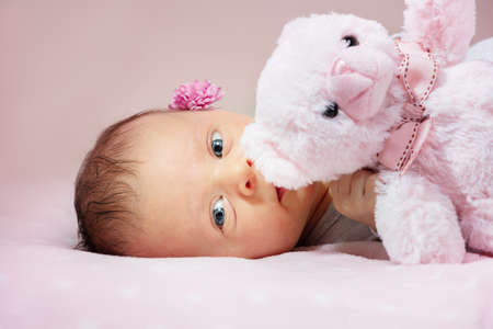 Newborn baby girl with pink teddy bear in handsの写真素材