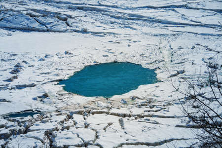 Ice-hole with snow in the frozen river at winterの写真素材