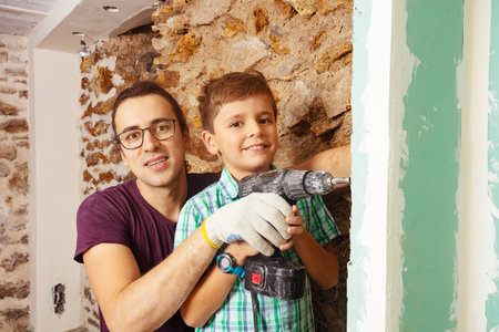 Father his son hold together screwdriver assembling DIY drywallの写真素材