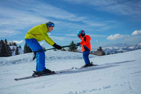 Instructor in skiing school glide backwards teach child to skiの写真素材